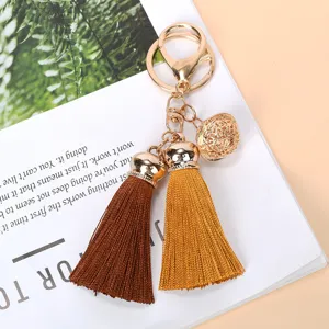 Close-up of golden hollow bell and double colored tassels on a stylish keychain charm