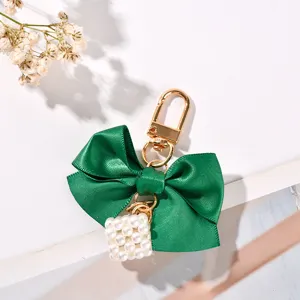 Close-up of green satin ribbon bow keychain with white pearl cube charm
