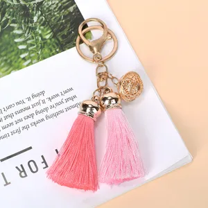 Macro view of a gold bell and pink tassel keychain on a decorative magazine page.