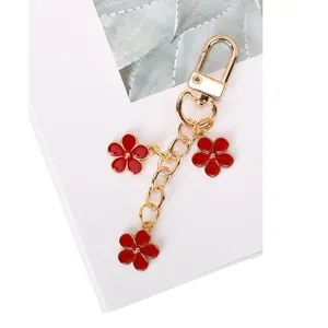 Elegant red enamel flower keychain featuring three floral charms in gold-tone alloy