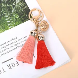 Close-up of gold filigree bell and dual-colored tassels on a keychain pendant