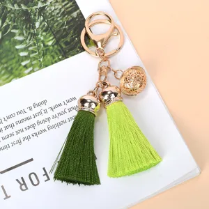Detailed macro shot of a golden hollow bell with dark and lime green silk tassels keychain