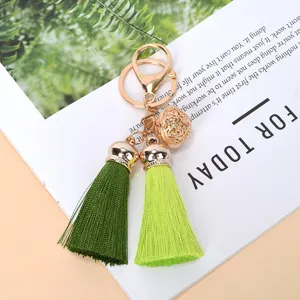 Detailed view of the double green tassel keychain with a golden hollow bell ornament.