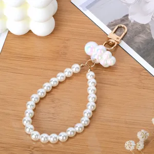 Detalle de llavero de perlas con dije de nube iridiscente y cierre dorado elegante.