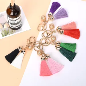 Detailed view of multiple colorful tassel keychains with golden bells and lobster clasps