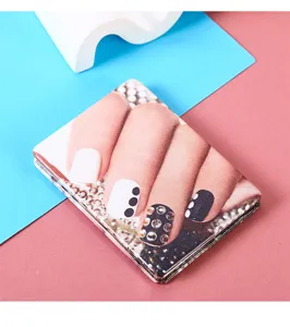 Detailansicht eines tragbaren Leder-Schminkspiegels mit Nailart-Muster auf blau-rosa Hintergrund
