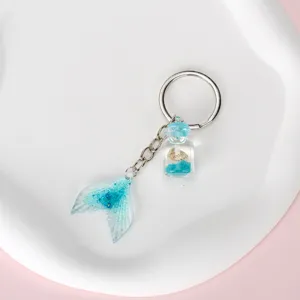 Detailed shot of mermaid tail keychain with gradient blue glitter and miniature shell bottle