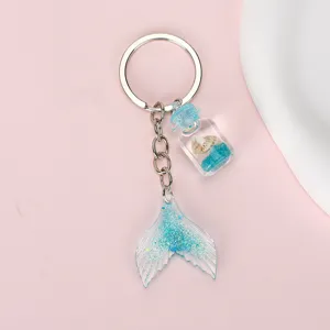 Detail of mermaid tail keychain with blue glitter finish and seashell bottle pendant