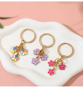 Detail view of colorful enamel flower keychain pendants in gold metal on white tray