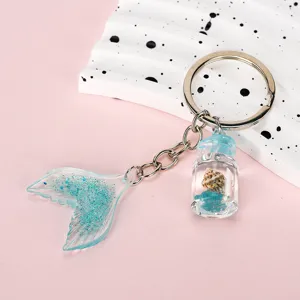 Close-up of a mermaid tail keychain with blue gradient glitter and a mini shell jar.
