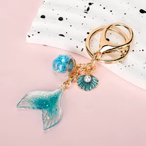Close-up detail of a vibrant blue mermaid fishtail keychain with glitter and ocean charms.