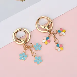 Detailed view of colorful enamel flower charms on gold-plated metal keychains for bags