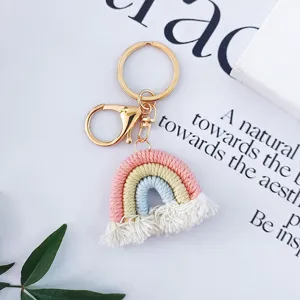 Gros plan d'un porte-clés arc-en-ciel tissé à la main avec pompons blancs en coton