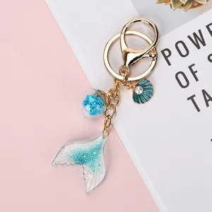 Close-up of a gradient blue glitter mermaid tail keychain with shell and star ball charms.