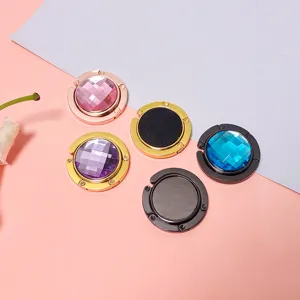 Close-up of portable foldable round metal handbag hooks in various gem-like colors