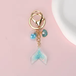 Detail view of the gradient blue mermaid tail keychain with shell and pearl charms