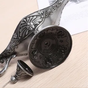Detail shot of the vintage metallic Aladdin lamp showing the ornate base and detached lid