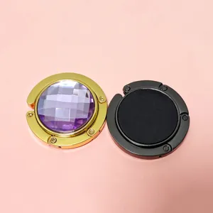 Two portable folding metal purse hooks shown in gold purple gem and matte black