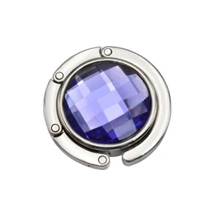 Close-up detail of a portable circular metal bag hook with faceted purple gemstone