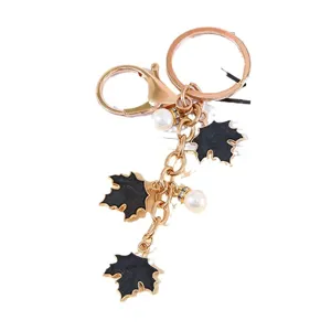 Golden metal maple leaf keychain with black enamel charms and white pearls