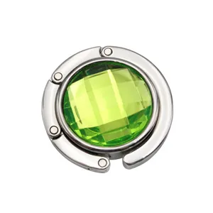 Detailed view of a foldable metal purse hook with a faceted green crystal center