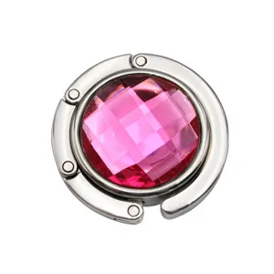 Close-up of portable folding metal bag hook with pink faceted crystal center