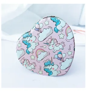 Detailed view of a portable heart-shaped mirror with cute cartoon unicorn pattern.