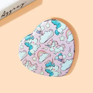 Close-up of a heart-shaped portable makeup mirror featuring cute unicorn patterns