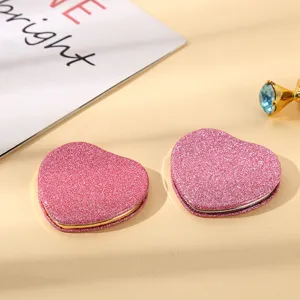 Detailed macro view of pink glitter heart-shaped portable compact makeup mirrors for women
