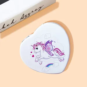 Close-up of a heart-shaped portable compact mirror featuring a cute cartoon unicorn.