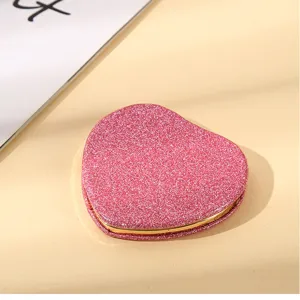 Detailed view of a pink glitter heart-shaped portable double-sided folding mirror