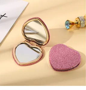 Detail view of a pink glitter heart-shaped double-sided folding pocket makeup mirror