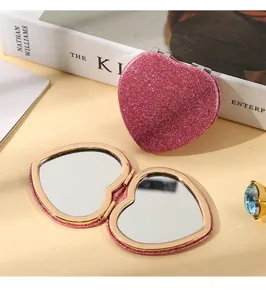 Close-up of pink glitter heart-shaped folding makeup mirrors with double-sided design.