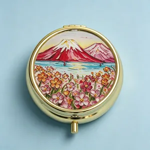 Macro view of the intricate Fuji mountain embroidery on a luxury golden round pill box lid