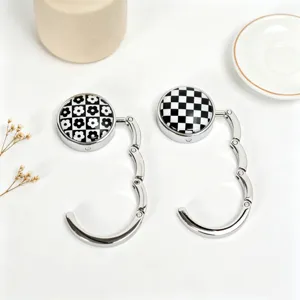 Macro view of portable foldable metal desk bag hooks featuring checkerboard and floral patterns