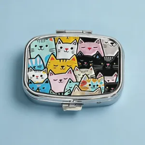 Compact square metal pill box featuring colorful cute cat illustrations on the lid