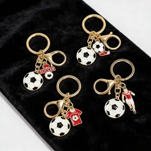 Detailed view of four unique golden metal soccer-themed keychains displayed on black velvet.