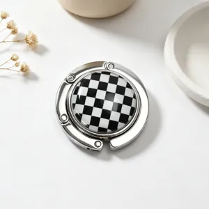 Detailed view of a portable foldable metal bag hook with a black and white checkered design