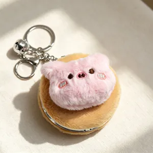 Vista dettagliata della testa di gatto in peluche rosa su uno specchio per trucco portatile