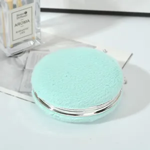 Dettaglio di specchietto da borsa rotondo in peluche verde menta con cornice
