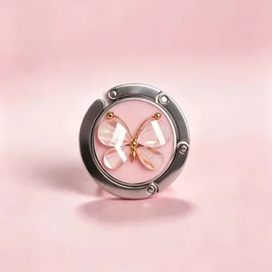 Nahaufnahme eines faltbaren Taschenhalters aus Metall mit elegantem rosa Kristallschmetterling