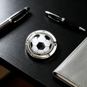 Nahaufnahme eines faltbaren Taschenhalters aus Metall mit klassischem Fußball-Design