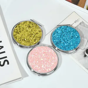 Vue détaillée de miroirs de poche ronds à paillettes en finitions or, bleu et rose