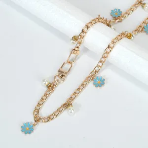 Détail de la bandoulière en métal doré avec marguerites bleues et perles