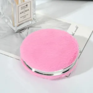 Vista dettagliata di uno specchio da trucco rotondo portatile coperto di pelliccia rosa
