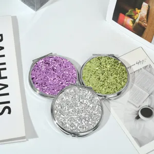 Vue de dessus de trois miroirs de maquillage ronds à paillettes violets, verts et argent