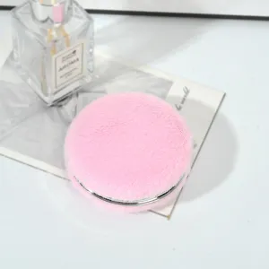 Primo piano di uno specchio da trucco rotondo a doppia faccia in ecopelliccia rosa