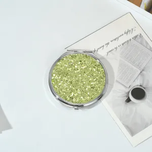 Vue détaillée des paillettes vert tilleul scintillantes sur un miroir de poche rond en métal.