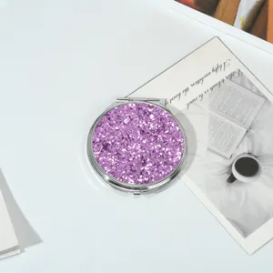 Vue détaillée d'un miroir de maquillage rose pailleté avec cadre en métal poli
