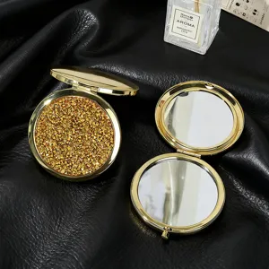 Close-up detail of golden glitter surface and double-sided folding makeup mirrors.